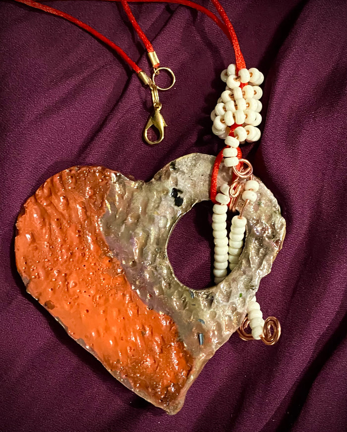 Have A Heart! Each heart pendant is handmade with love! It is 3"x 3"and weighs approx. 3ozs. This pendant has a red,orange, white and copper metallic raku glazes that renders a unique translucent patina. The heart has a textured pattern . Both sides are are different and equally beautiful! There is a spiral white mini beads on copper in the center. This pendant has a nice 12" red adjustable rattail cord!
