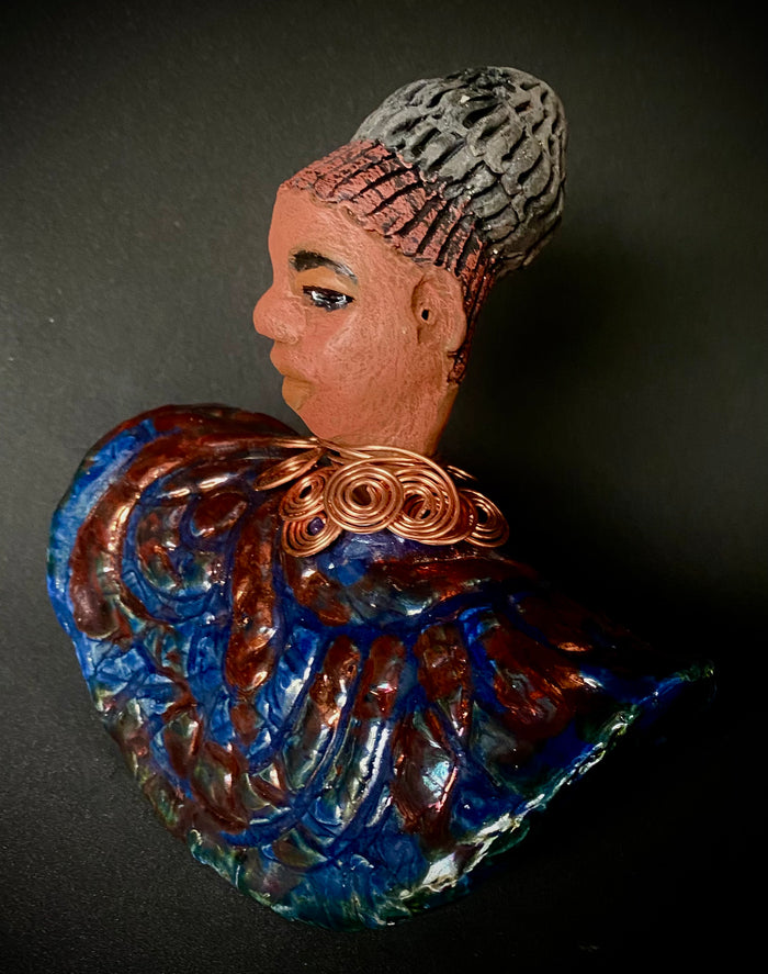 Meet Tia! Tia looks up with joy and anticipation! Tia stands 7" x 6" x 4" and weighs 1.90 lbs. She has a beautiful textured copper and blue robe. Tia has braided clay hair up in a bun. She has a honey brown complexion and soft light brown lips. Tia will make for great conversation in your home. Free Shipping! Check out our Shipping and Return policy