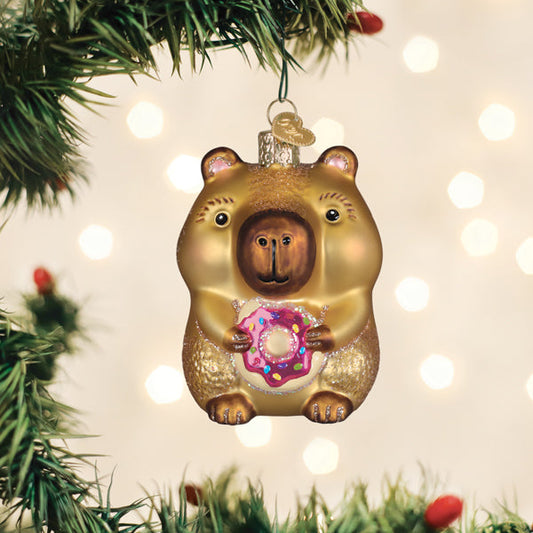 Capybara eating a donut glass Christmas ornament hanging on a tree
