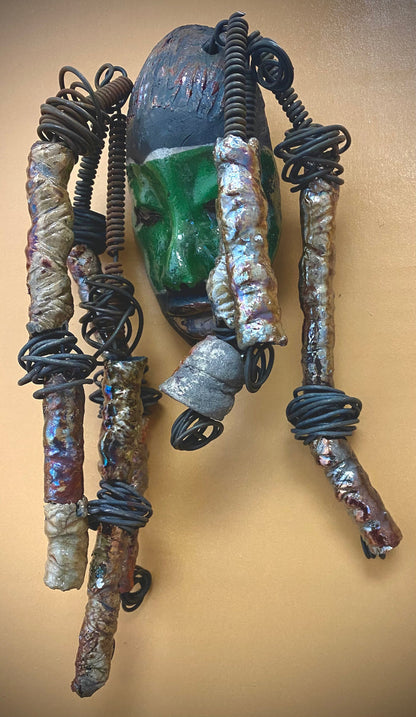 Meet Craig! I am going to make more with colors in the face like Craig. I like how the green and copper complements each other.  I started making art soon after seeing authentic African artwork at the Smithsonian Museum of African Art. I was in total awe. Craig was inspired by my visit there.  Craig is   4"x 10" and weighs 12 ozs. He has a two tone  green and copper face. Craig has hand coiled 16 gauge wire  hair with over  10 metallic raku beads.