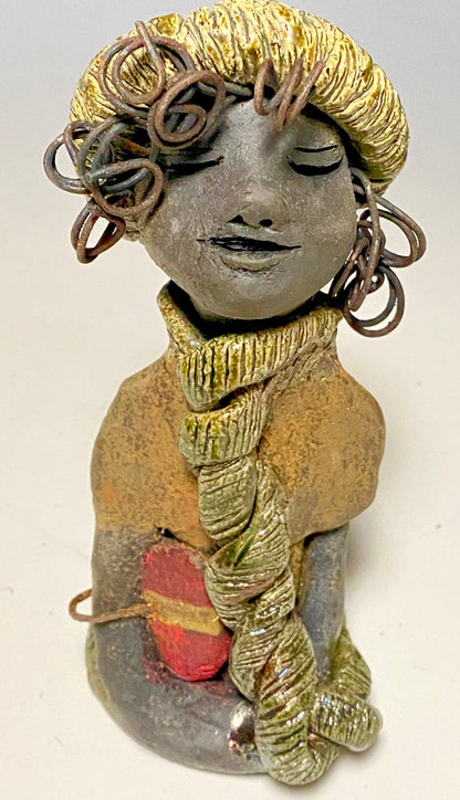 Meet Edna! Edna stands 6" x 3.5”x 4" and weighs  12.4 ozs.  She has a dark lovely smokey black complexion. Edna has a glossy green and copper metallic dress.  She clinches her designer  Dark red purse. Edna wears a designer hat as well. With the current situation we All are going through,  Edna will place a smile on your face during this challenging time.  If not return Edna within 30 days after receiving her for a complete refund.