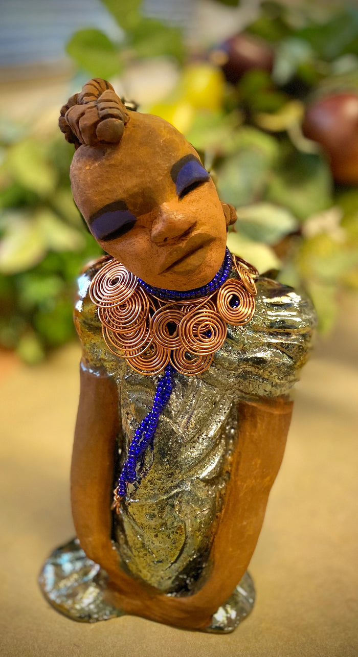 Georgia stands 11" x 5" x 3" and weighs 2.15 lbs. She has a honey brown complexion with a braided tribal clay hairstyle. She has an awesome copper metallic glitzy dress. Georgia has her long loving arms folded as she rest and waits.  Give  Georgia special place inside of your home.