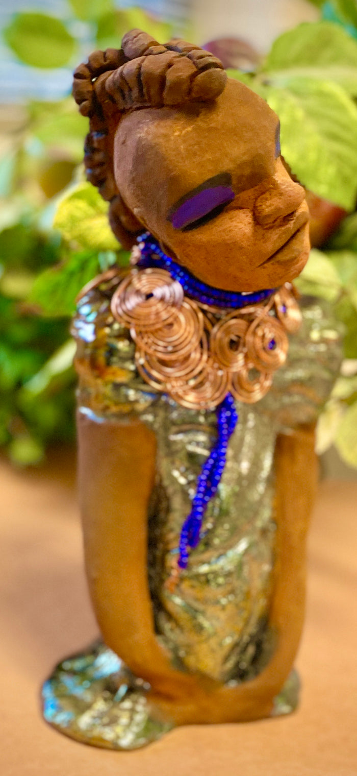 Georgia stands 11" x 5" x 3" and weighs 2.15 lbs. She has a honey brown complexion with a braided tribal clay hairstyle. She has an awesome copper metallic glitzy dress. Georgia has her long loving arms folded as she rest and waits.  Give  Georgia special place inside of your home.