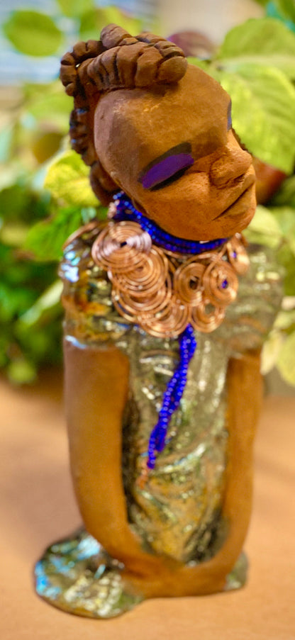 Georgia stands 11" x 5" x 3" and weighs 2.15 lbs. She has a honey brown complexion with a braided tribal clay hairstyle. She has an awesome copper metallic glitzy dress. Georgia has her long loving arms folded as she rest and waits.  Give  Georgia special place inside of your home.