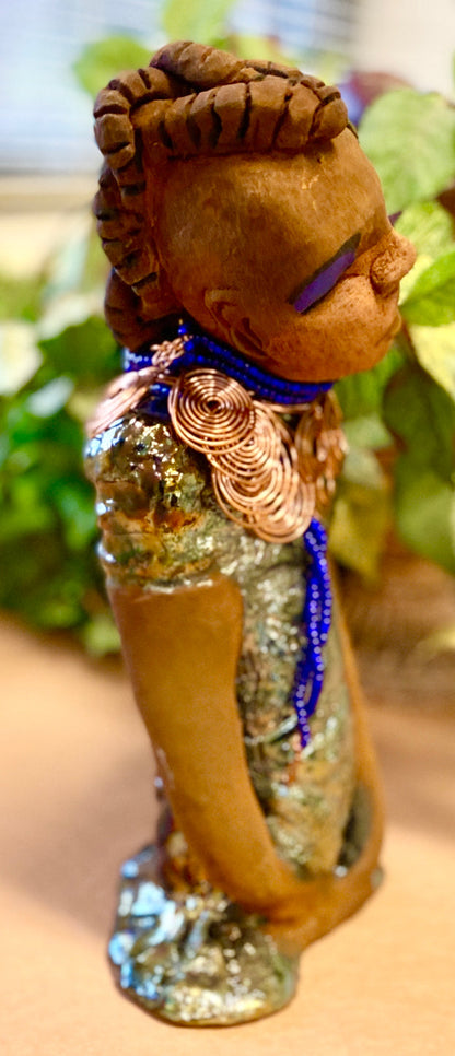Georgia stands 11" x 5" x 3" and weighs 2.15 lbs. She has a honey brown complexion with a braided tribal clay hairstyle. She has an awesome copper metallic glitzy dress. Georgia has her long loving arms folded as she rest and waits.  Give  Georgia special place inside of your home.