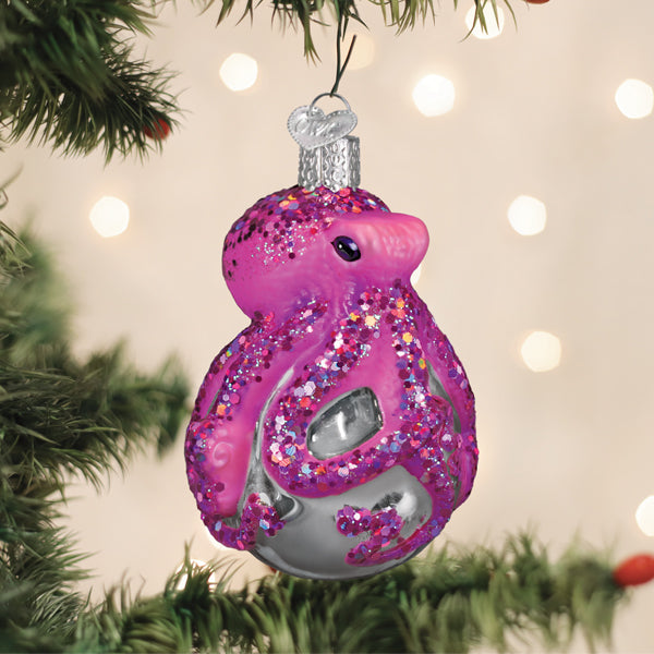 Shimmering octopus glass ornament with glittered arms wrapped around a gift